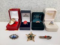 Overall lot showing four rings in boxes and three brooches and pins
