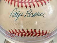 Close-up of Ralph Branca autograph on the baseball in blue ink, with another faint signature below it.