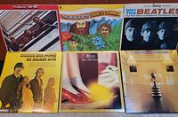 Six collectible vinyl albums displayed in two rows of three, including The Beatles, The Beach Boys, Mama's and Papas, and Electric Light Orchestra albums.