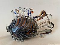 Side view of a large art glass fish sculpture showing multicolored swirled glass body with clear glass fins and detailed dorsal fin.