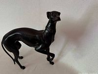 Full side view of bronze greyhound/whippet figure showing stance and raised front paw.