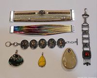 Full lot showing seven jewelry items: three bracelets and four pendants on a white background.