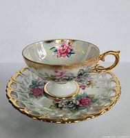 Close-up view of porcelain teacup and saucer showing detailed floral pattern and gold trim