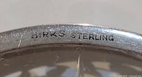 Close-up photo showing 'BIRKS STERLING' hallmark stamped on the base of a coaster.
