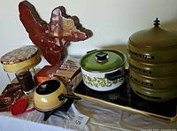 Wood decor clock, electric fondue set, vintage stackable metal containers labeled Flour, Sugar, Coffee, Tea, coasters, and vintage recipe booklets shown on table.