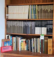 Wide shelf view showing multiple sets of hardcover books, including Time Life series in beige, black, blue, and white spines, and assorted travel and atlas books of varying sizes and colors.