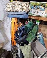 Camping tents and supplies including tents in bags, fold-out chair, blankets, and kids pool boxed