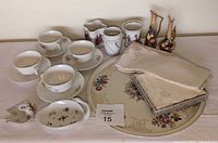 Wide shot showing porcelain soap dish, jewelry tray, Rosenthal Winifred serving platter, stack of linens, matching tea cups with saucers, and small vases in background.