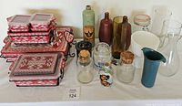 Full display of all items on the table showing Temptations casserole set on left and assorted jars, bottles and vases on right