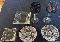 Photo of two vintage Imperlux Lausitzer Germany crystal bohemian goblets with purple cut grape and leaf designs, and four ashtrays (two Czech star pattern crystal and two vintage glass). Items displayed on dark fabric background.