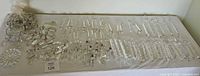 Top-down view of many assorted clear crystal chandelier parts laid out on a white cloth.