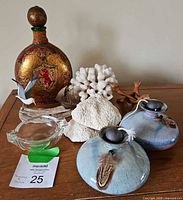 Full view of the lot showing vintage decanter with stopper, coral art, two pottery oil lamps, and ashtray on a wooden surface