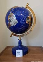 Photo of the full globe showing the continental map, blue oceans, and gold-tone hardware on a blue base.