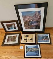 Overview of all six framed nature landscape photographs on floor against wall, including Yosemite Falls large piece, two Navajo Falls, and three smaller unsigned prints.