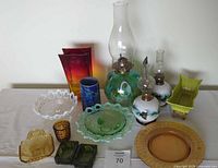 Full display of lot with all ceramic and glass items including oil lamps, bowls, vases, platter, and chip & dip dishes