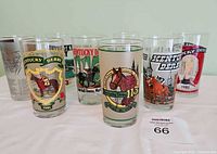 Eight Kentucky Derby themed vintage glasses arranged in two rows, showing fronts with colorful graphics including horse racing scenes and year stamps.