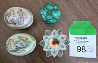 View of two painted Lenox Easter eggs, hexagonal malachite box, and clear crystal flower figurine on wood surface