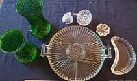 Clear Indiana Glass divided relish dish platter with handles, two green textured MCM vases, two clear glass small dishes, and a crescent moon shaped plate on dark surface.
