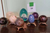 Full set of eight spheres and one egg on display stands, with varied colors and patterns.