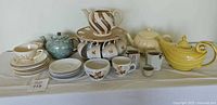 Complete tea set including yellow Hall teapot, Japanese mini teapots, Lazy Susan with hanging cups, and assorted saucers and cups.
