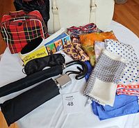 Lot of vintage travel accessories laid out including scarves, umbrellas, Miracle Brush, and picnic bag