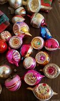 Assorted vintage glass ornaments in various shapes and colors on a wooden surface