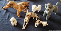 Seven porcelain dog figurines arranged on blue cloth