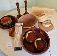 Full lot view showing multiple wood bowls, cutting utensil box, bamboo steamer, skewers, and cork trivet on a white surface.