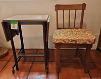 Photo of wooden chair with floral cushion next to metal typewriter stand with wooden top and caster wheels.