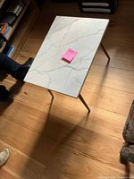 Photo of first white marble top end table showing marble pattern and three metal legs.