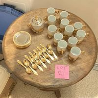 Top view of full set on round wooden table including cups, saucers, spoons, and sugar bowl with lid.