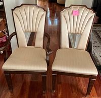 Two dining chairs side by side showing upholstery and wooden legs, one with armrests and one without