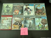 Photo showing 8 PlayStation 3 game cases arranged in two rows of four with a pink sticky note labeled 'LOT 18'.