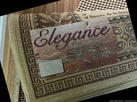 Close-up photo of rug label showing brand 'Elegance' and material '100% Heatset Polypropylene Yarn'.