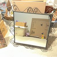 Large black wrought iron square mirror with decorative scrollwork in frame.