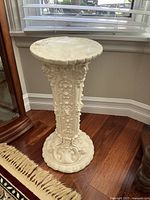 Full view of the decorative plaster pedestal showing detailed carvings and overall condition.