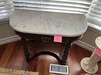 Front angle view of wooden table with marble top and single drawer, showing turned legs and curved stretcher base.