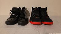 Black high-top patent Darth Vader sneakers and black/red Jordan sneakers side by side