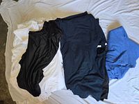 Mixed pile showing white, black, navy and blue tees