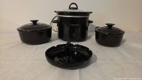 Group shot of Crock-Pot slow cooker, two Le Creuset pots with lids, and ashtray