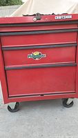 Front of red Craftsman rolling chest showing lock, logo, three-drawer layout, casters