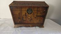 Full view of wooden storage box front with painted scene and clasp