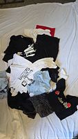 Pile of assorted t-shirts spread on bed