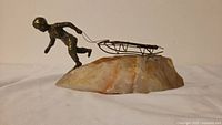 Bronze boy figure towing sled on stone base