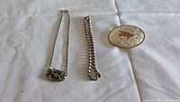 Overall view of two necklaces and belt buckle on white background