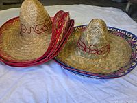 Stacked straw sombreros—five with red trim, five with blue/purple trim