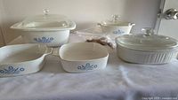 All five Corning Ware casserole dishes with three glass lids displayed on table