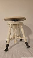 Full view of white painted swivel piano stool with turned legs and claw feet