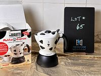Bialetti Mukka Express cappuccino maker next to original branded box with visible cow print and logo.
