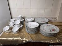 Overall view of the full set including stacked teacups, saucers, bowls, and plates on a countertop.